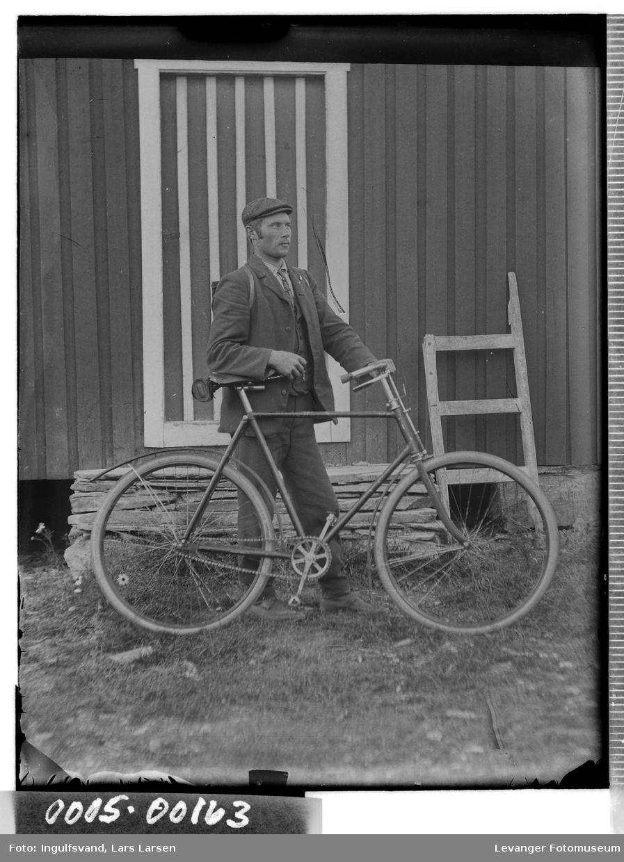 Portrett av mann med sykkel foran en trapp med en sladd i bakgrunnenen.