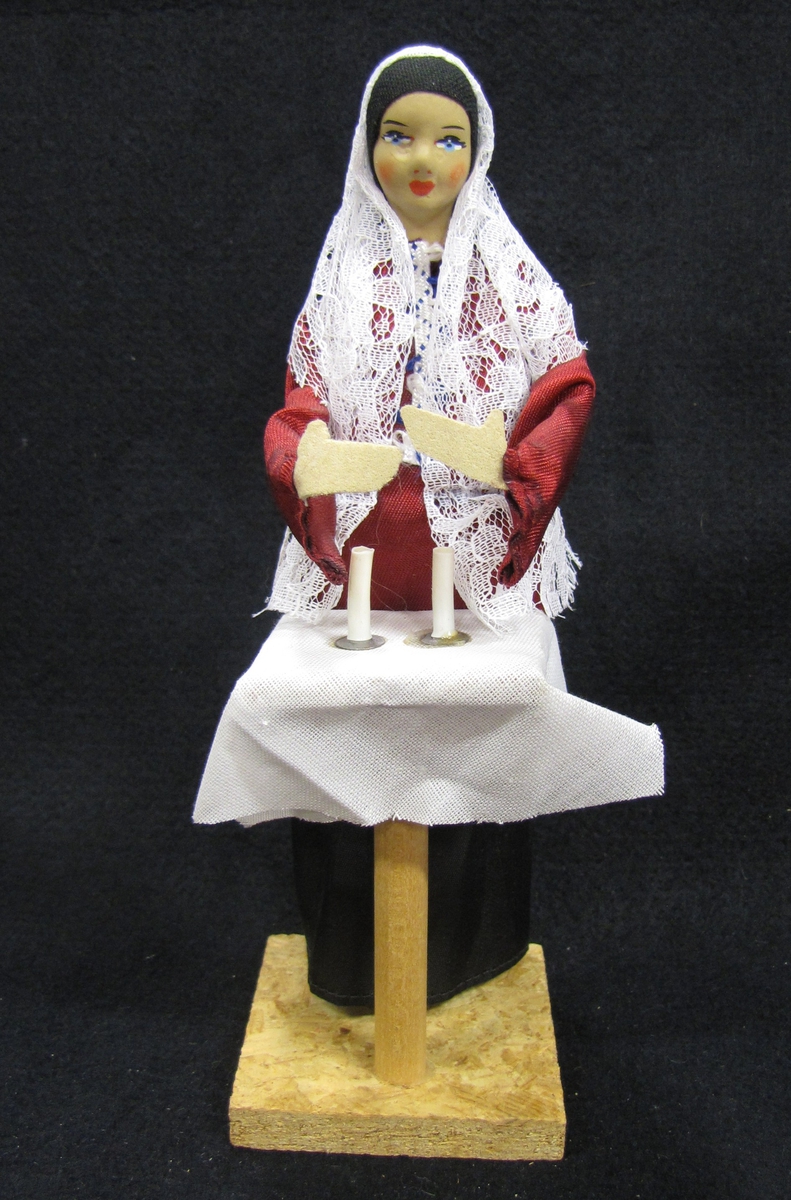 21 736:51  Docka föreställande en kvinna klädd i judisk dräkt med svart lång kjol, röd blus och vit huvudduk av spets. Kvinnan står framför ett pelarbord med två ljus över vilka hon håller händerna. Material: Trä, textil, keramik. Tillverkad av ''Sabra'' i Israel. Inköpt av Ebba Lundström i Israel 1977 och skänkt till ägaren. H. 20,5 cm.

Dockan ingår i en samling med 106 dockor från olika länder.

Ägarinnan började samla dockor på 1930-talet.Under de kommande åren kom hon allt mer att inrikta samlandet på souvenirdockor som inköptes under resor, framförallt i Frankrike.

Samlandet fortsatte fram till 1980-talet. I hemmet var de flesta dockorna uppställda i monter eller på hyllor.

Under flera år förestod ägarinnan Älvsborgsslöjd i Trollhättan.