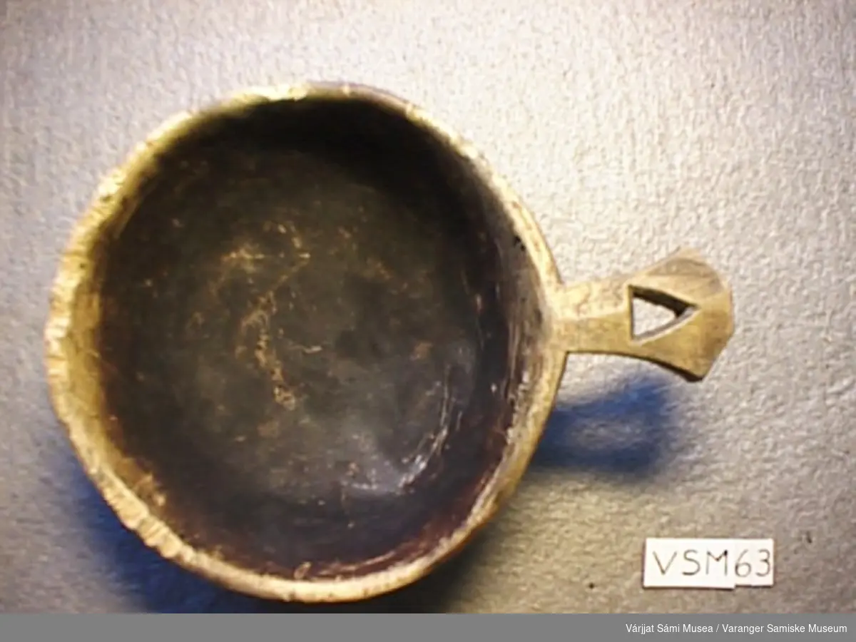 Koppen er laget av tre. På hanken er det skjært et trekantformet hull. På bunnen av koppen står følgende datering 8.11.1934
