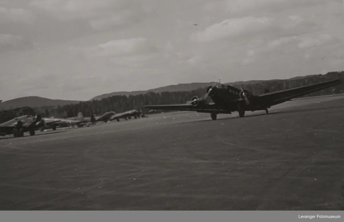 Taksende fly på rullebanen av typen Junkers 52, Junkers 52 og Heinkel 111 i bakgrunnen.