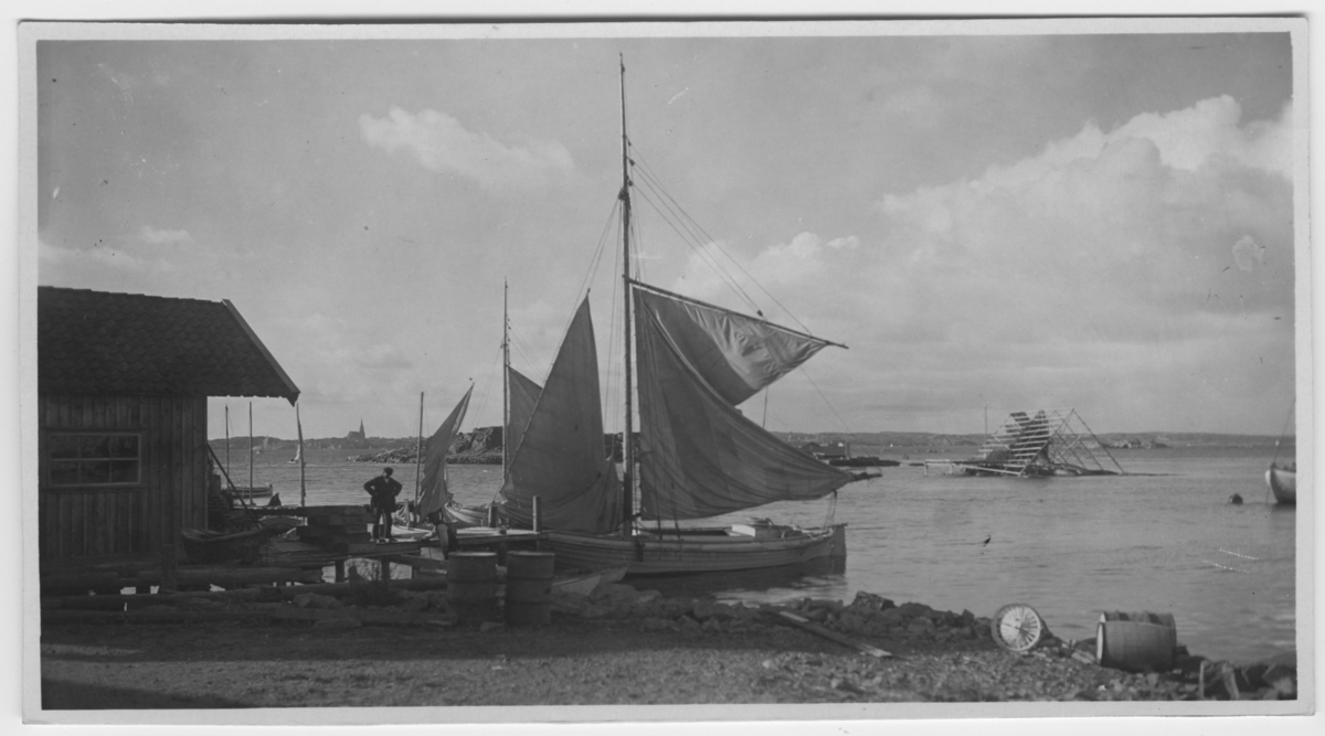 'Henrikssons brygga, Lysekil i fonden N.N.V Båtar vid brygga, 1 man står på bryggan. I vattnet torkställning för fisk. ::  :: Serie fotonr 1888-1963.'