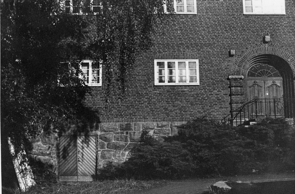 'Göteborgs Naturhistoriska museum oktober 1978: :: Södra tegelväggen av Göteborgs Naturhistoriska Museum, valvformad ingång med staket och träport i stensockeln. ::  :: Ingår i serie med fotonr. 5527:69-216.'