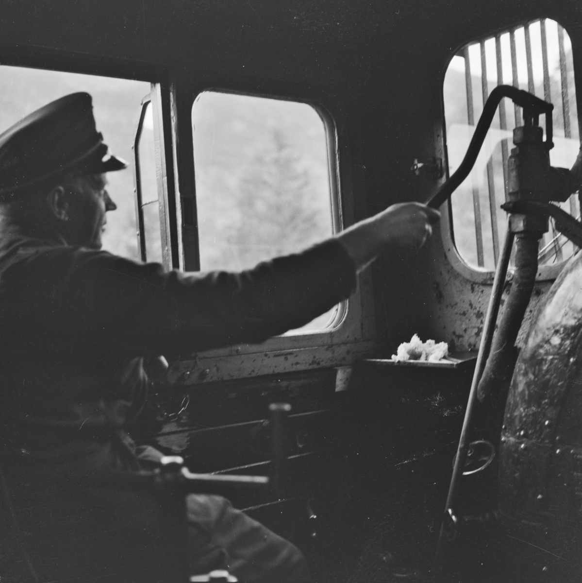 Fyrbøteren på sin arbeidsplass omdord i damplokomotiv 21e 207 på på Numedalsbanen.