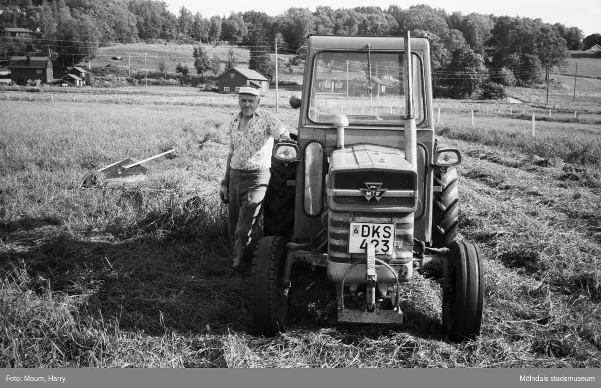 Olle Svensson i Lindome vid sin traktor, år 1983. "Slåttern är i full gång. Olle Svensson tar en paus i körningen."

För mer information om bilden se under tilläggsinformation.