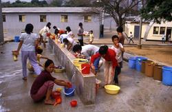 Kvinner og barn vasker klær i Tuen Mun flyktningeleir i Hong
