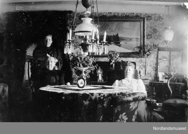 Interiørbilde fra Kjerringøy. Fra venstre Sofie Amundsen, Anna Elisabeth Kristiansen (stående) og Elise Gotaas, deres mor. 