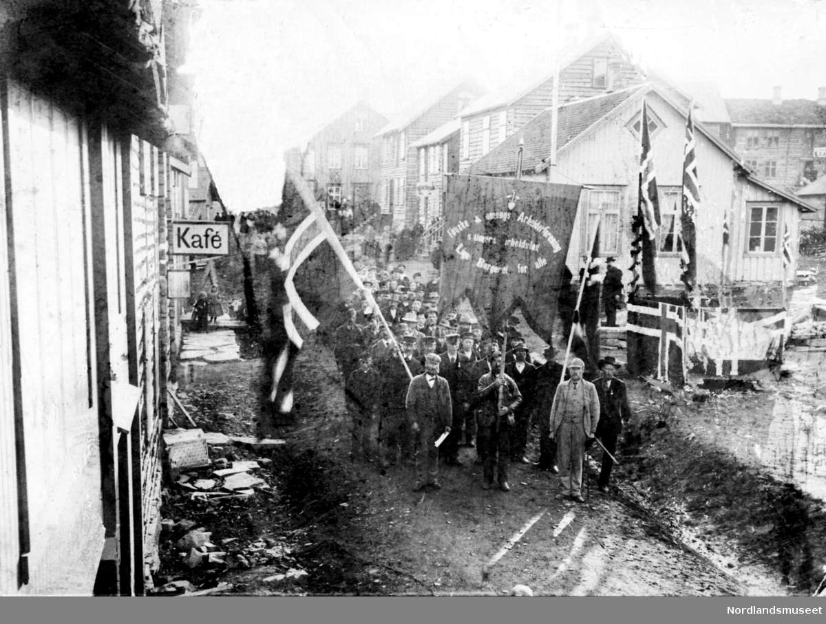 Demonstrasjonstog første mai med flagg og fane i Storgata på Fauske. Fremst til venstre er Peder Wollum.