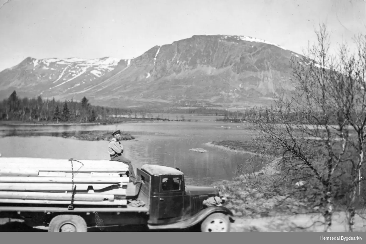 Sjåføren Trond Wøllo har teke seg ein pause på toppen av eit stort materiallass ved Hestaneåni med Helsingvatn og Skogshorn i bakgrunnen.
