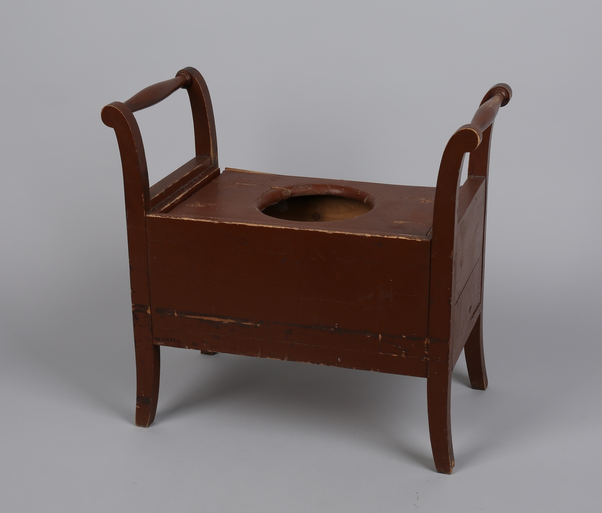 Rektangulær stol uten ryggstø (krakk). Dreide, utoverbøyde håndtak på sidene. Lokk med hull til potte/dobøtte.