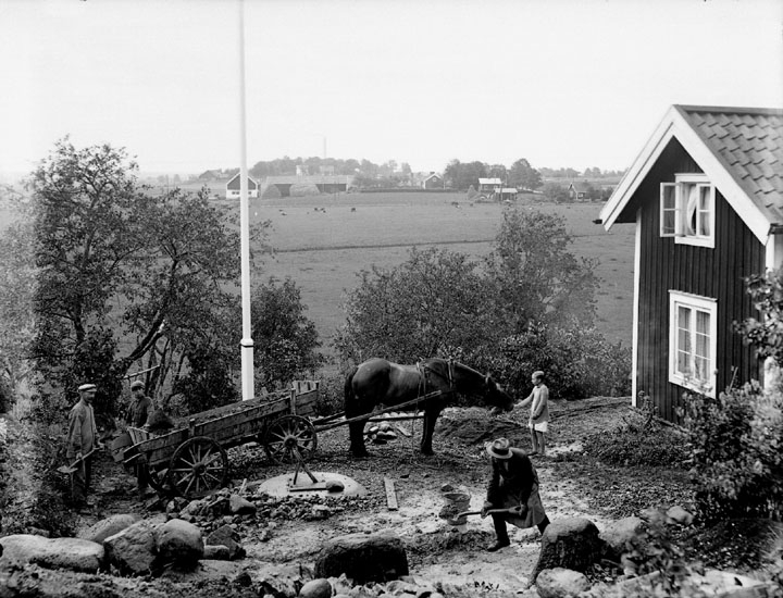 Jordbearbetning, fyra personer, en häst spänd för vagn.
Sommarstuga.
Fotograf Sam Lindskog