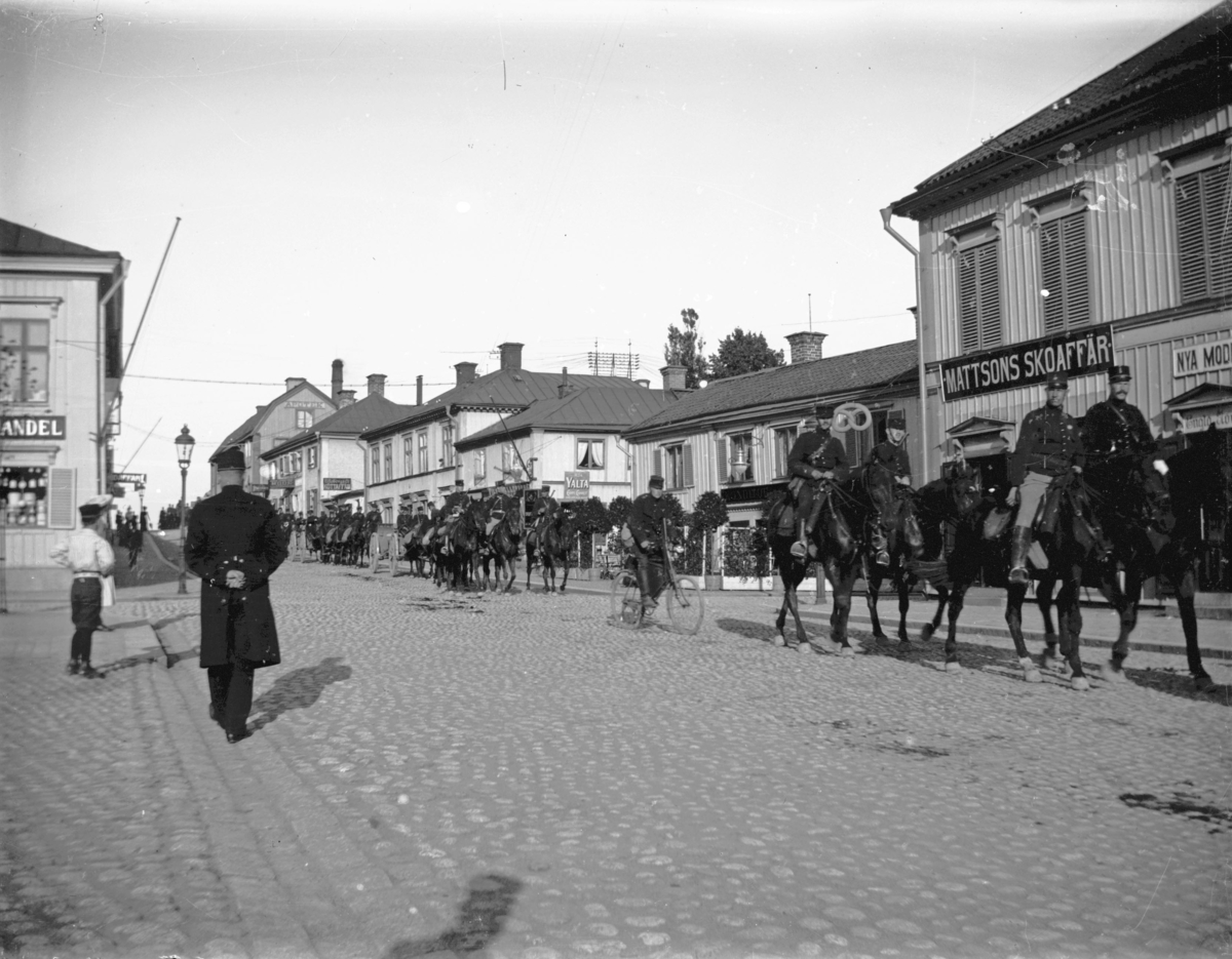 Militärtrupp på häst nedför Kungsgatan, Enköping, vy från torget mot öster, ca 1908.