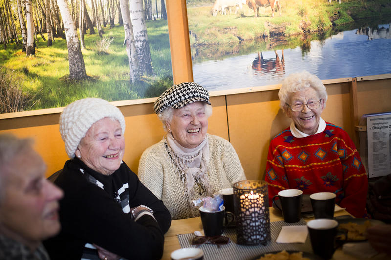 Foto av eldre mennesker som drikker kaffe inne i kafeen på besøkssenteret