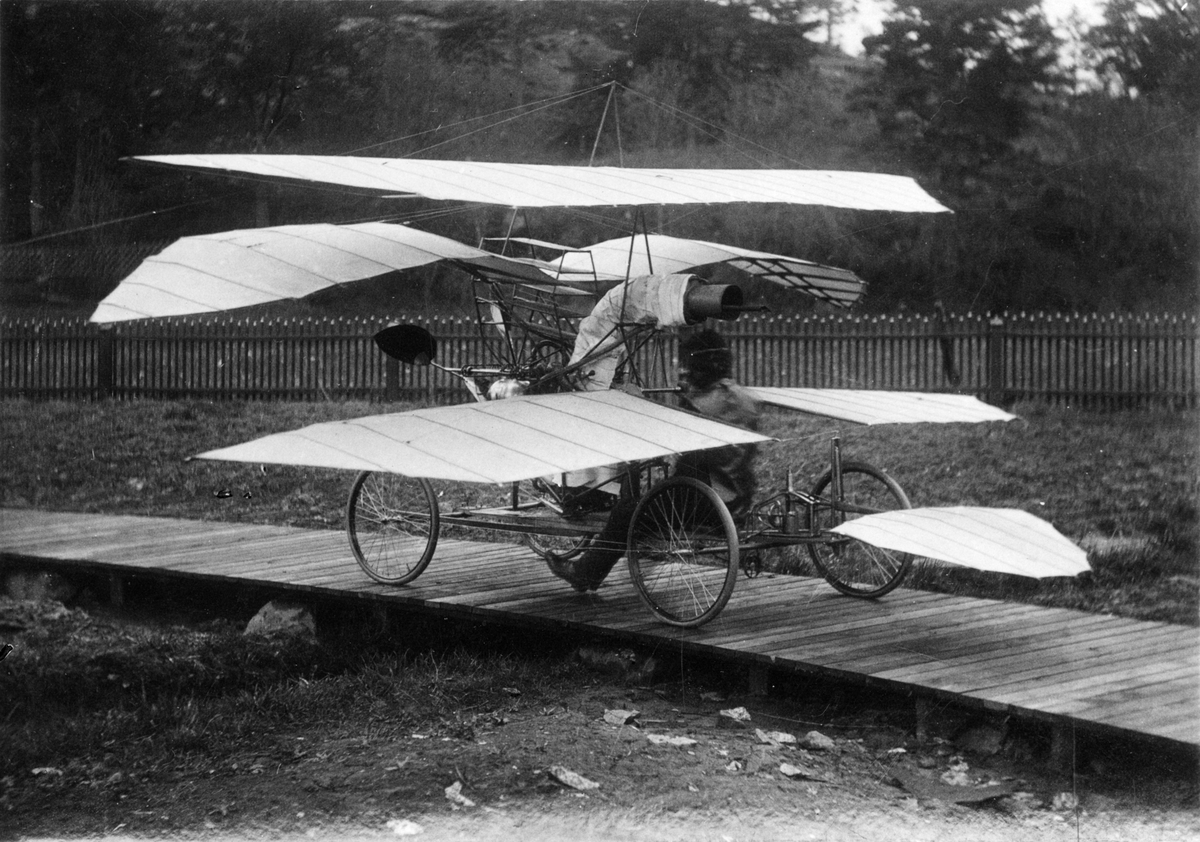 C. R. Nybergs flygmaskin på karusellbanan. Flygmaskinens propeller drevs av en ångmaskin med rörångpanna. Nybergs försök gick ut på att framförallt på att studera vingprofiler, styr- och stabiliseringsorgan samt luftmotståndet.