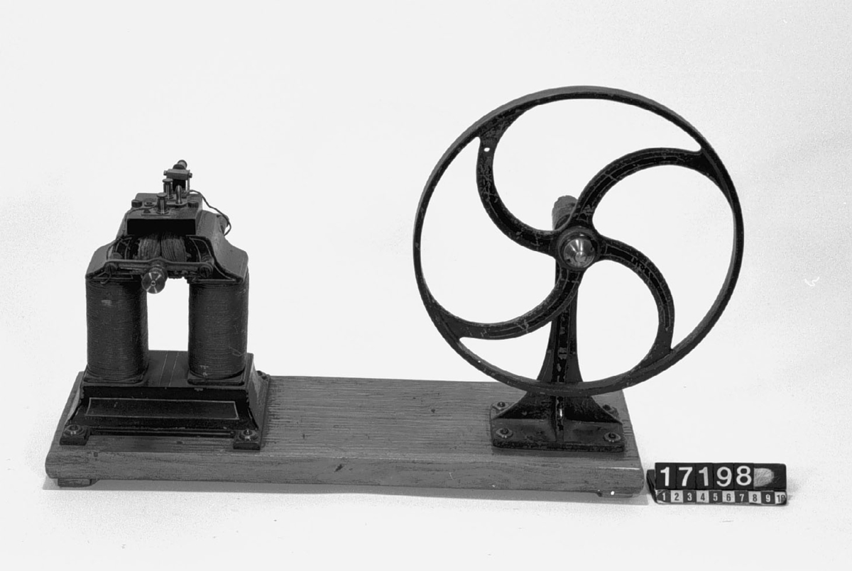 Demonstrationsmodell av likströmsgenerator/dynamo, monterad med balanshjul för remdrift. Vevhandtag saknas.