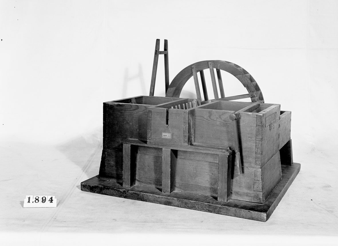 Modell av tegelslagningsmaskin. Text på föremålet: "XVI.B.1. E-b-5 N:o 179. E.b.1.5. Murbruks och Lerbråka".
