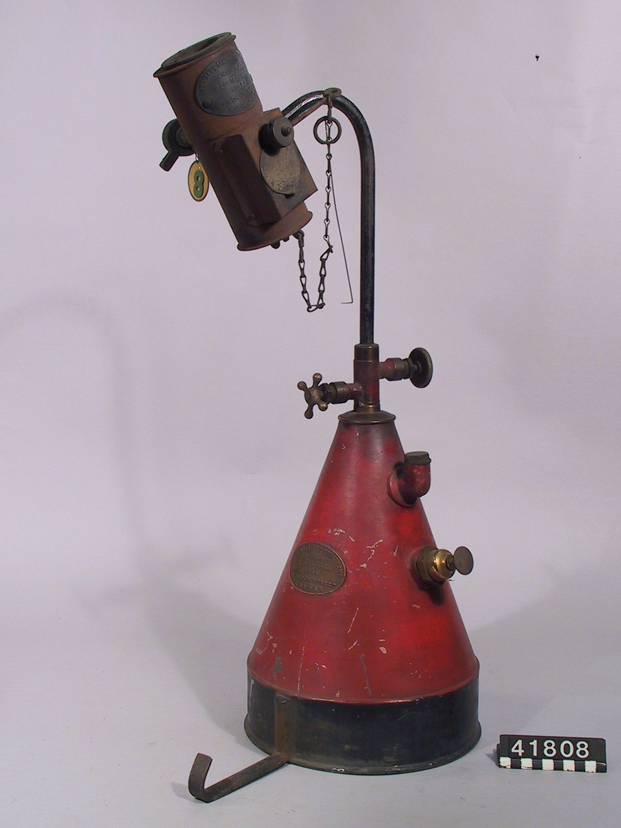 Lödlampa av stål. Skylt på brännaren: Sinclairs Little Comet Lamp. Reversible Reg No 287011 1896. Eldon Street London. Bifogat etikett No 8.