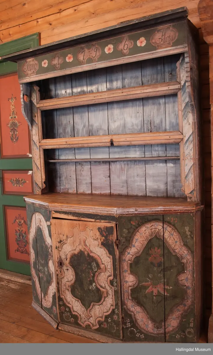 Marmorert toppstykke over felt med fem fyllinger.  Feltet grønnmalt med røde og hvite blomster.  Fyllingene, hvit bunn, sortmalte bokstaver og tall:  Anno 1796 H. Sata.  Overskapet har to hyller med lister og en smal hylle med profilert kant.  Bakveggen hvitmalt med rester etter mørkere undermaling, sideveggene marmorert.  Underskapet tredelt, fremspingende midtparti som er dør.  Fyllinger på de tre delene.  Grønn bunnfarge.  Slitt rosemaling, hvitt og rosa.  Profilert gulvlist.  Nøkkelhull med beslag og defekt lås av jern.  En hylle innvendig.