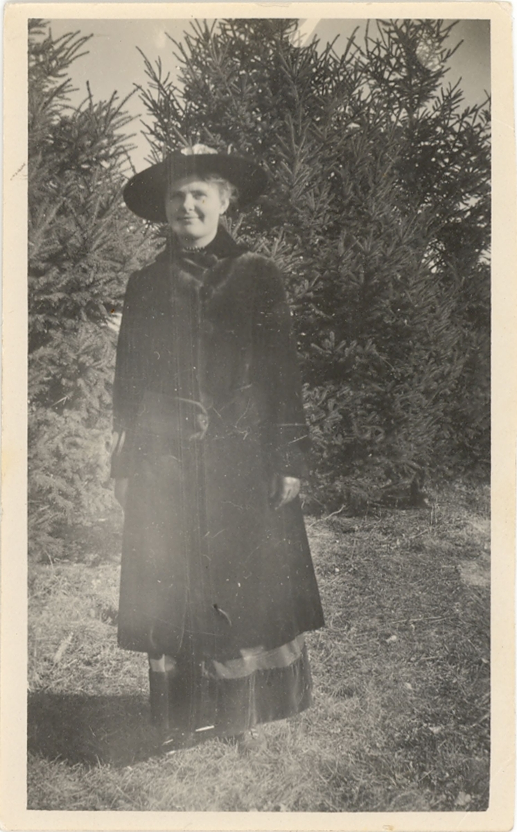 Ukjent kvinne i Amerika fotografert ute i naturen m. kåpe og hatt.