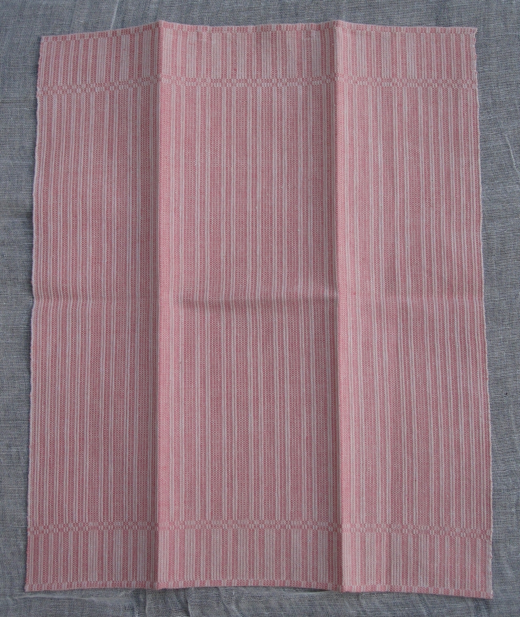 Handvävd handduk i halvdräll i rosa och vitt. Bomull i varp och lin i inslag. Vävd hank i rött och vitt.