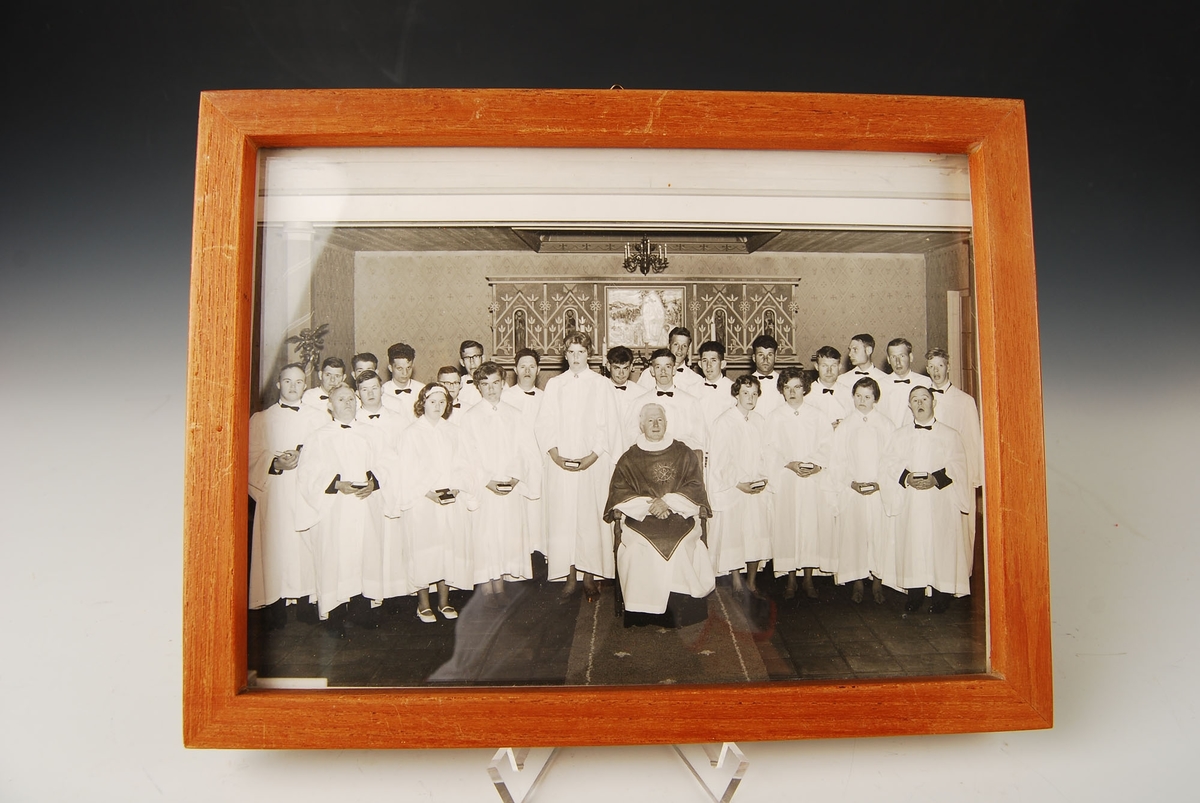 Konfirmasjon i Bakkebø kirke. 

25 konfirmanter står oppstilt i kirken, sammen med presten som sitter foran i en stol. 

19 gutter og 6 jenter.