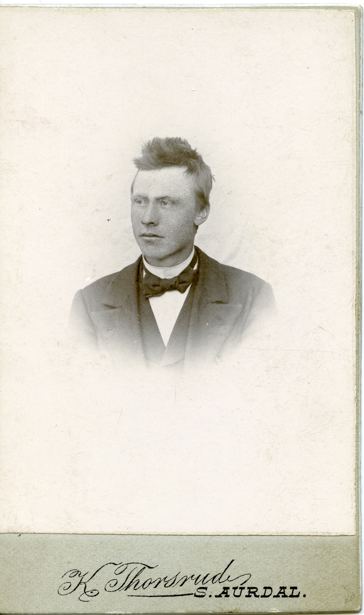 Halvportrett av mann iført dress med skjorte og sløyfe.