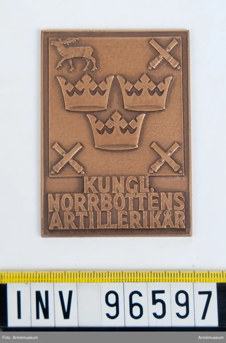Plakett i brons för Norrbottens artillerikår.
Stans 13824, härdad 1942-04-19.
Reducering, puns och stans till plakett, 52x72 mm. Tre kronor jämte korslagda kanoner och ren, jämte inskription KUNGL: NORRBOTTENS ARTILLERIKÅR.
Modell av Eugen Erhardt.