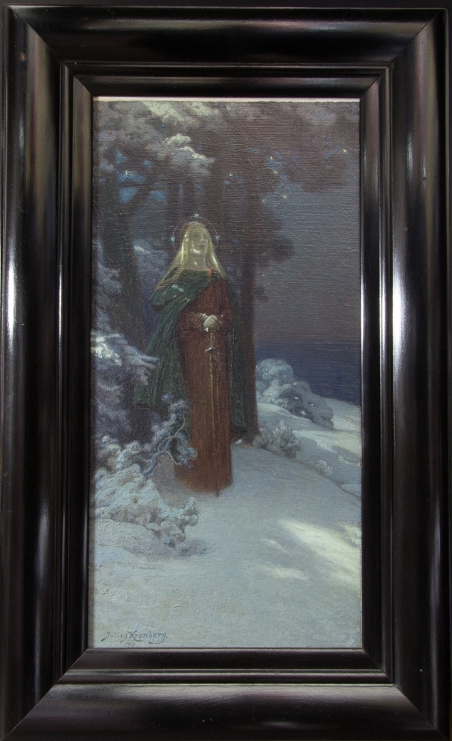 Ung kvinna, helfigur, med lång rödbrun klänning och lång svart kappa stående i ett snötäckt landskap med tallar och skuggor på snön från solen.