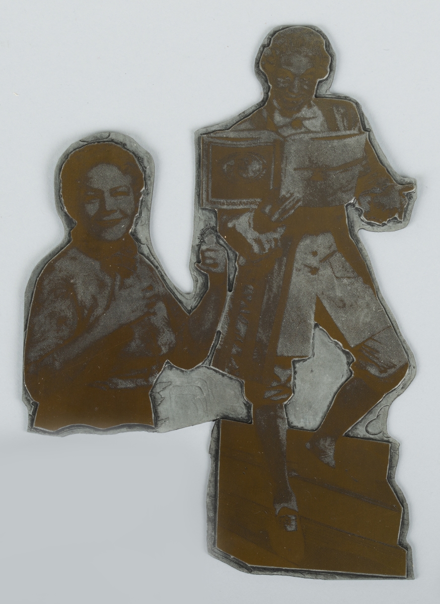 Trykkplate av metall med motiv av to personer. Platen er formet etter motivet.
