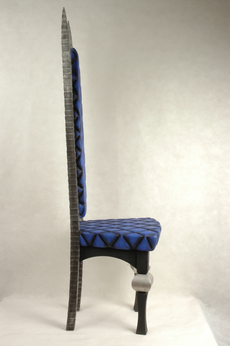 Trestol med høy rygg. Sete og rygg i blått og svart rutemønster. Rutene er skåret inn i treverket.