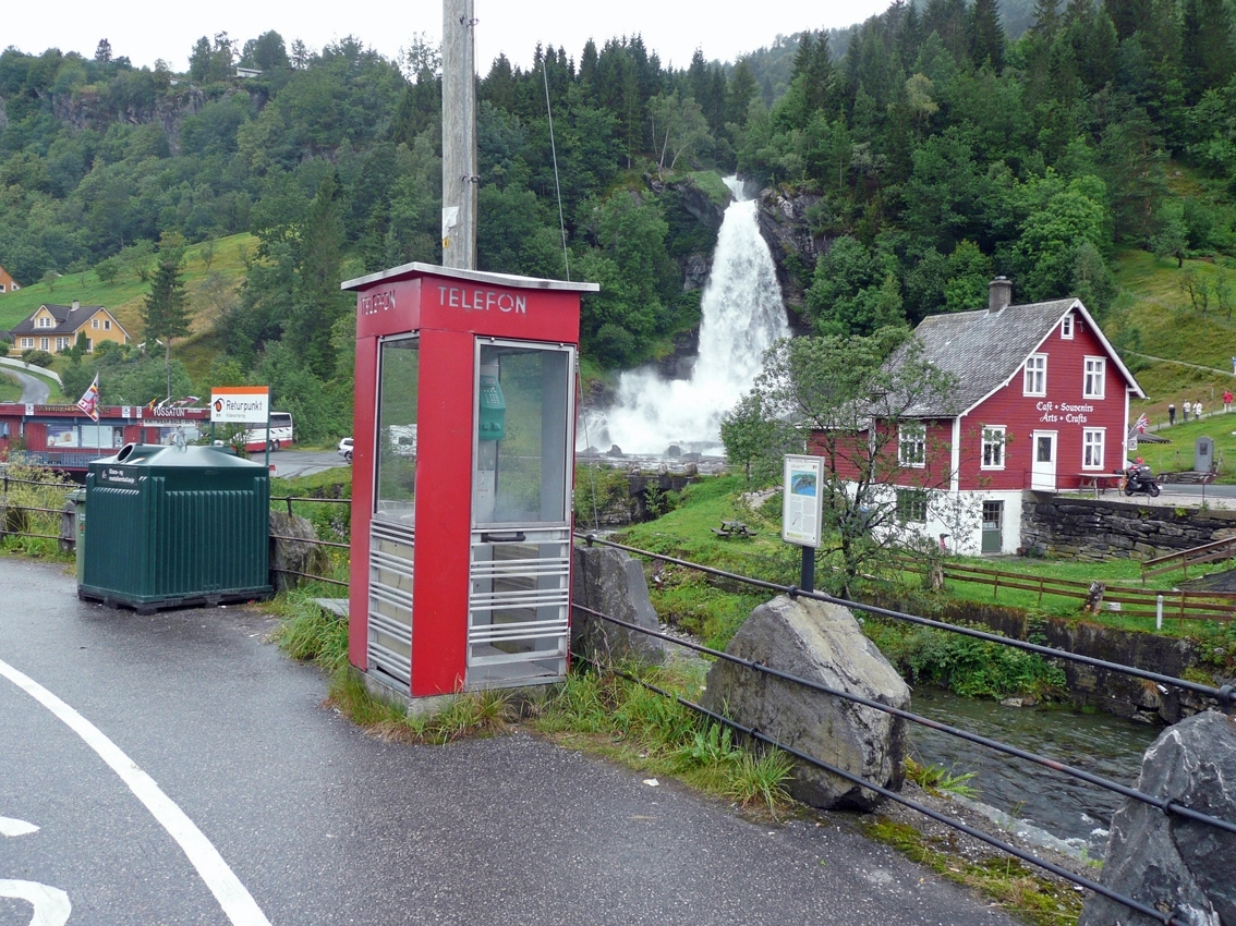 Telefonkiosken står ved Steindalsfossen i Nordheimsund, og er en av 100 vernede telefonkiosker i Norge. De røde telefonkioskene ble laget av hovedverkstedet til Telenor (Telegrafverket, Televerket). Målene er så å si uforandret. 
Vi har dessverre ikke hatt kapasitet til å gjøre grundige mål av hver enkelt kiosk som er vernet. 
Blant annet er vekten og høyden på døra endret fra tegningene til hovedverkstedet fra 1933.
Målene fra 1933 var:
Høyde 2500 mm + sokkel på ca 70 mm
Grunnflate 1000x1000 mm.
Vekt 850 kg.
Mange av oss har minner knyttet til den lille røde bygningen. Historien om telefonkiosken er på mange måter historien om oss.  Derfor ble 100 av de røde telefonkioskene rundt om i landet vernet i 1997. Dette er en av dem.