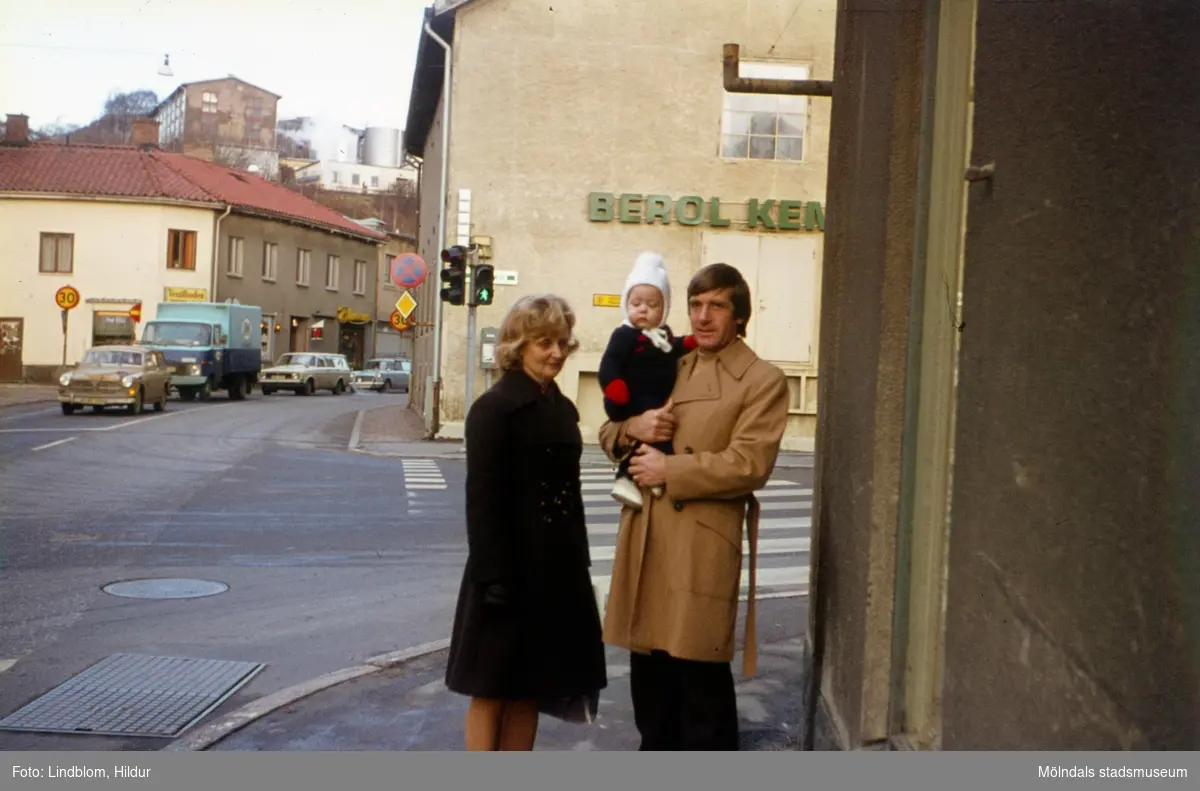 En kvinna och en man utanför Rasmussons skoaffär vid Gamla Torget i Mölndal med adress Kvarnbygatan 4, 1970-tal. Mannen håller ett barn i famnen. I bakgrunden till vänster ses Kvarnbygatan 45 och i mitten Kvarnbygatan 6 (Berol Kemi). Till höger går Forsebron in.

För mer information om bilden se under tilläggsinformation.