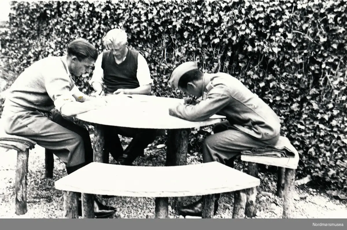Tre soldater som sitter ved et bord og skriver. Brevskriving?