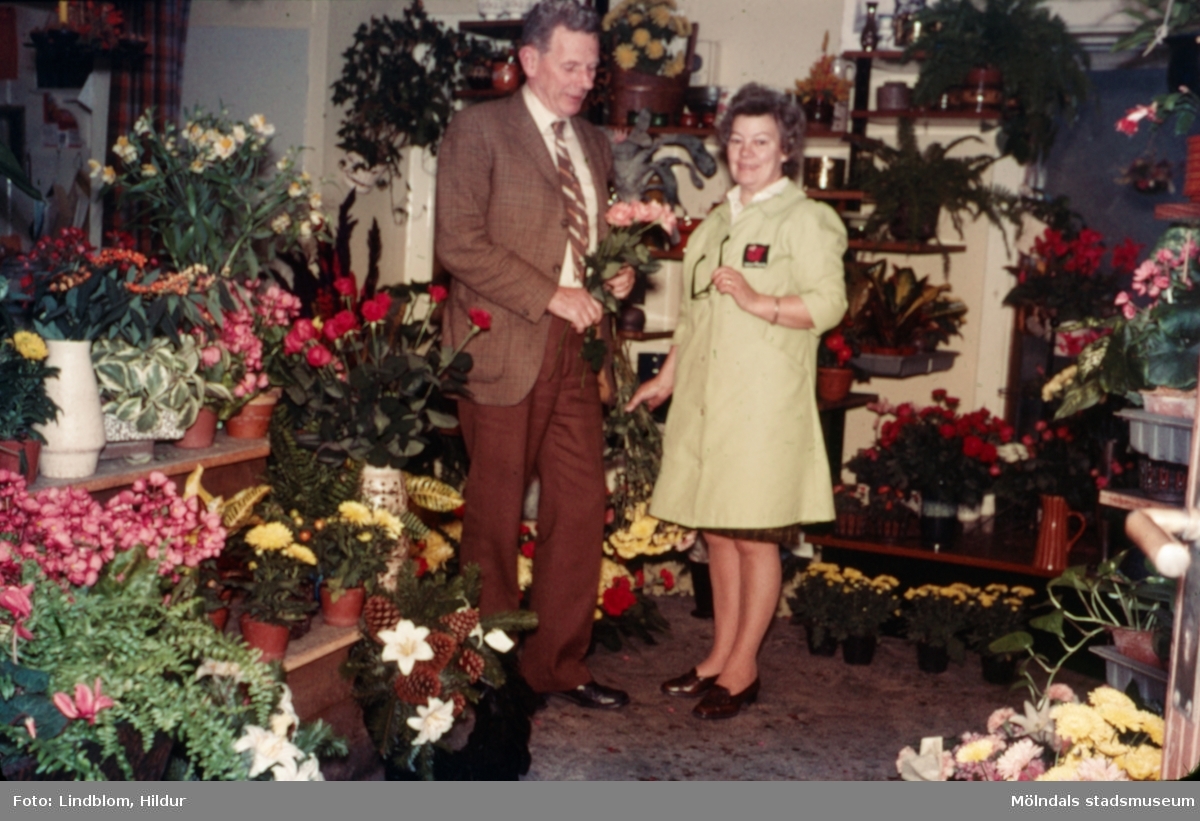 En man och en kvinna fotograferade i blomsteraffären vid Gamla Torget i Mölndal med adress Kvarnbygatan 45, 1970-tal. Kvinnan hette Kerstin och var ägare av affären. Lokalen används numera av Corpus Pizzeria.

För mer information om bilden se under tilläggsinformation.