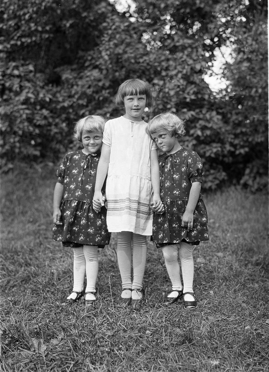 Portrett av tre jentunger.  Jenta i midten er ikke identifisert, men på hver sin side har hun tvillingene Bjørg og Olaug Lunden, uten at det kan sies hvem er hvem av de to. Deres mor var Nora Lunden, født Nøkleby, fra gården Kraby østre.