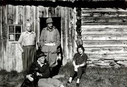 Foto av en gruppe mennesker samlet utenfor en eldre tømmerby