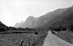 En vei strekker seg gjennom en dal. En bil er parkert ved ve