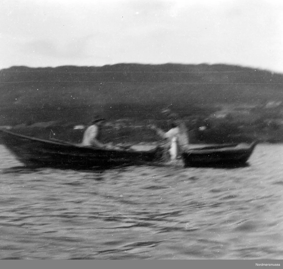 Uklart bilde av en robåt ute på fjorden en plass i Møre og Romsdal, med ...