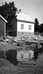 Bolighus ved strandkanten, vi kan se kanten av et naust til 