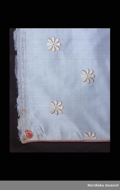 Huvudliggaren;
"Tygrulle, siden. Blå parpsatin, lanserat mönster kypert. Blå botten, vita sexflikiga blommor, bruna konturer. Stockholms hallstämpel svart, röd lackstämpel. Tillverkad ca 1810."