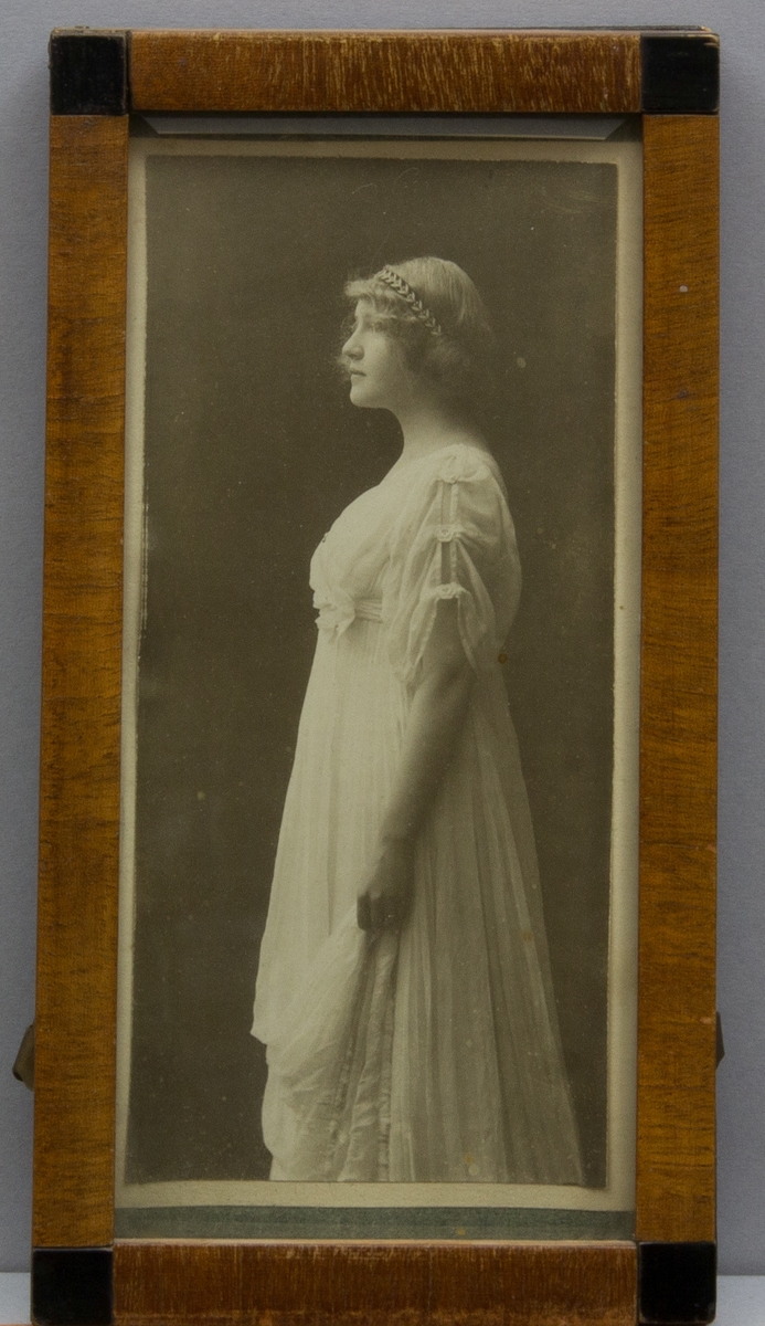 Fotografi föreställande Margherita Kronberg, "Greta", helfigur i ljus hellång klänning.