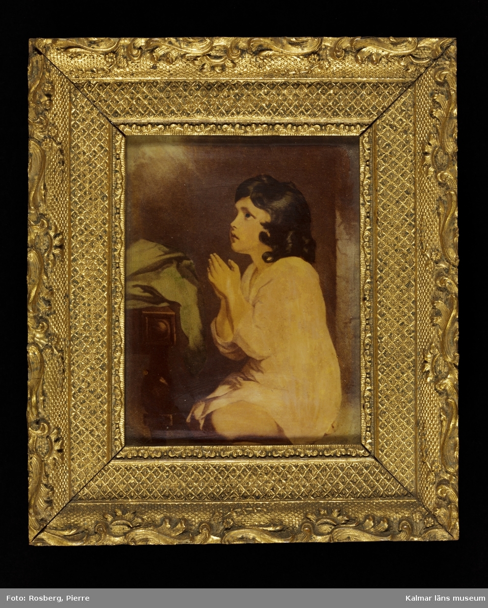 KLM 8981 Tavla. Ramad. Målning på glas. Motiv med bedjande gosse. Utförd av en fröken Liljegren i Kalmar, död på 1880-talet. Fröken Liljegren brukade måla dylika.