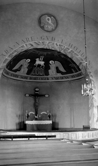 Foto av ett altare och en ljuskrona i taket samt kyrkbänkar.