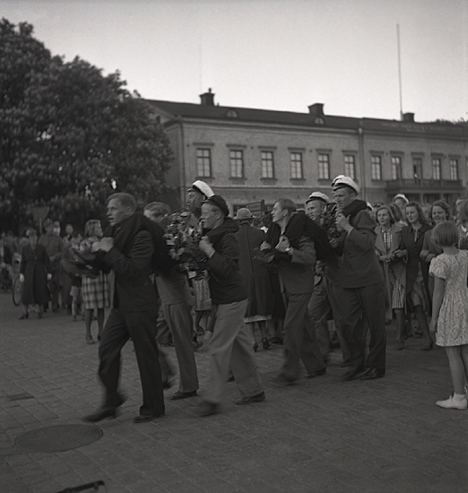 Studenterna, 1939.  Två studenter bärs iväg iväg utmed Stortorget. I bakgrunden syns Residenset.