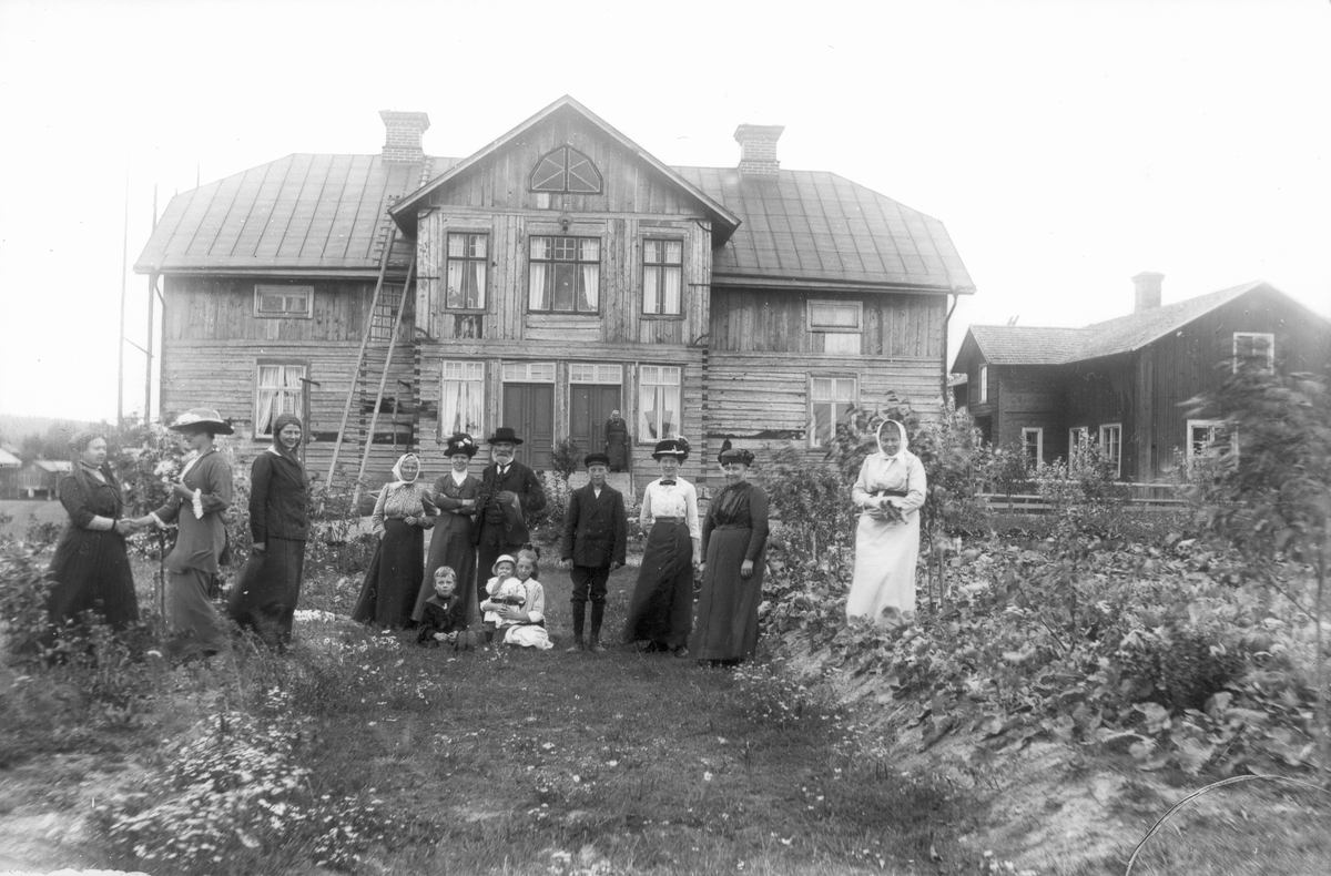 Skinnars, Lenninge 6:14. Byggnaden till höger bortriven på 40-talet. Tredje kvinnan från höger är Brita Persson, längst till höger Marta Hansson. I mitten med skärmmössa Evert Svedlund.