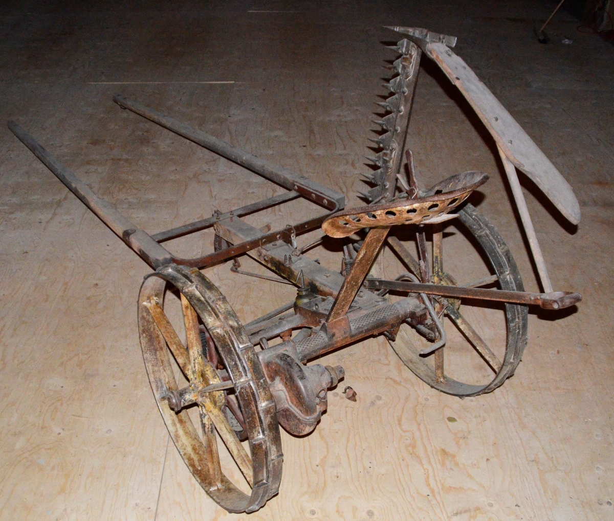 Slåmaskin for hest med drag. 6-eika metallhjul. Sete. Jarn, utan draget, som er i tre.