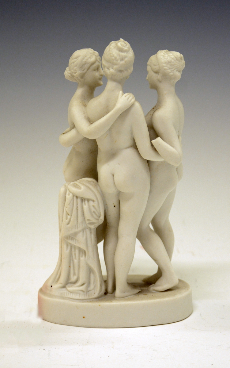 Tre nakne kvinner på sokkel med en liten søyle med klede bak. Uglasert.