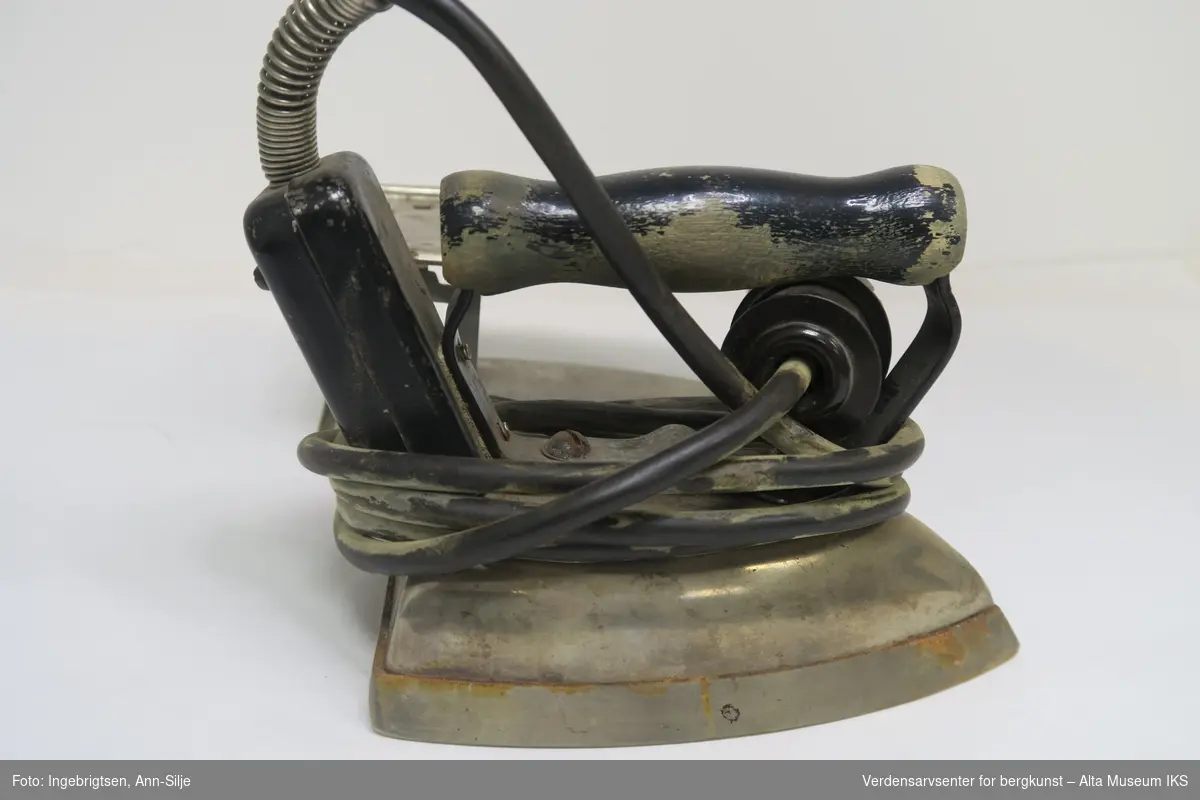 Form: Elektrisk strykejern med stativ. I enden er det koblet en ledning i jernet.