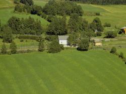 Kulturlandskap. Dyrka mark. Lyseblått bolighus, hvitmalt sta