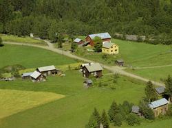 Moslykkja foran i bildet: Brun tømmerbygning, mange små uthu