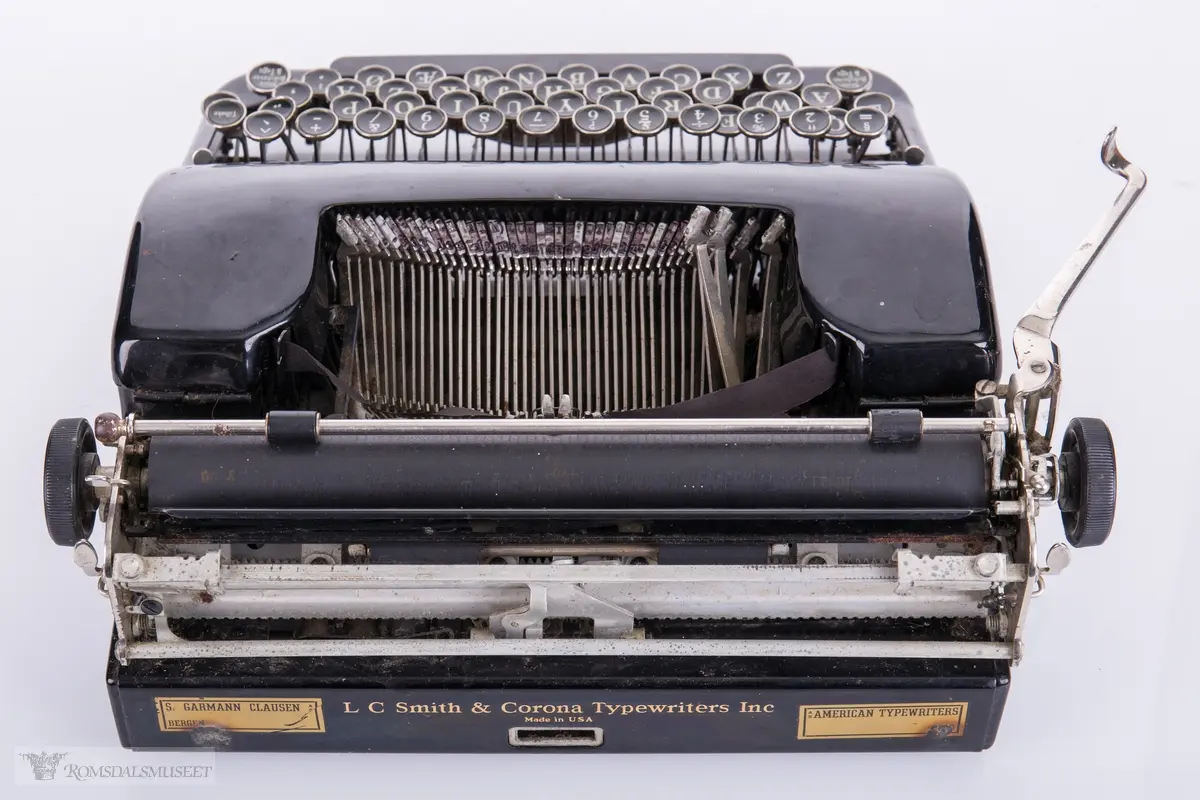 Mekanisk skrivemaskin med 49 tangenter. Plastkarosseri med avrundede kanter. Maskinen har en kvadratisk oppbevaringskasse med låsemekanisme og bærehåndtak i lær.